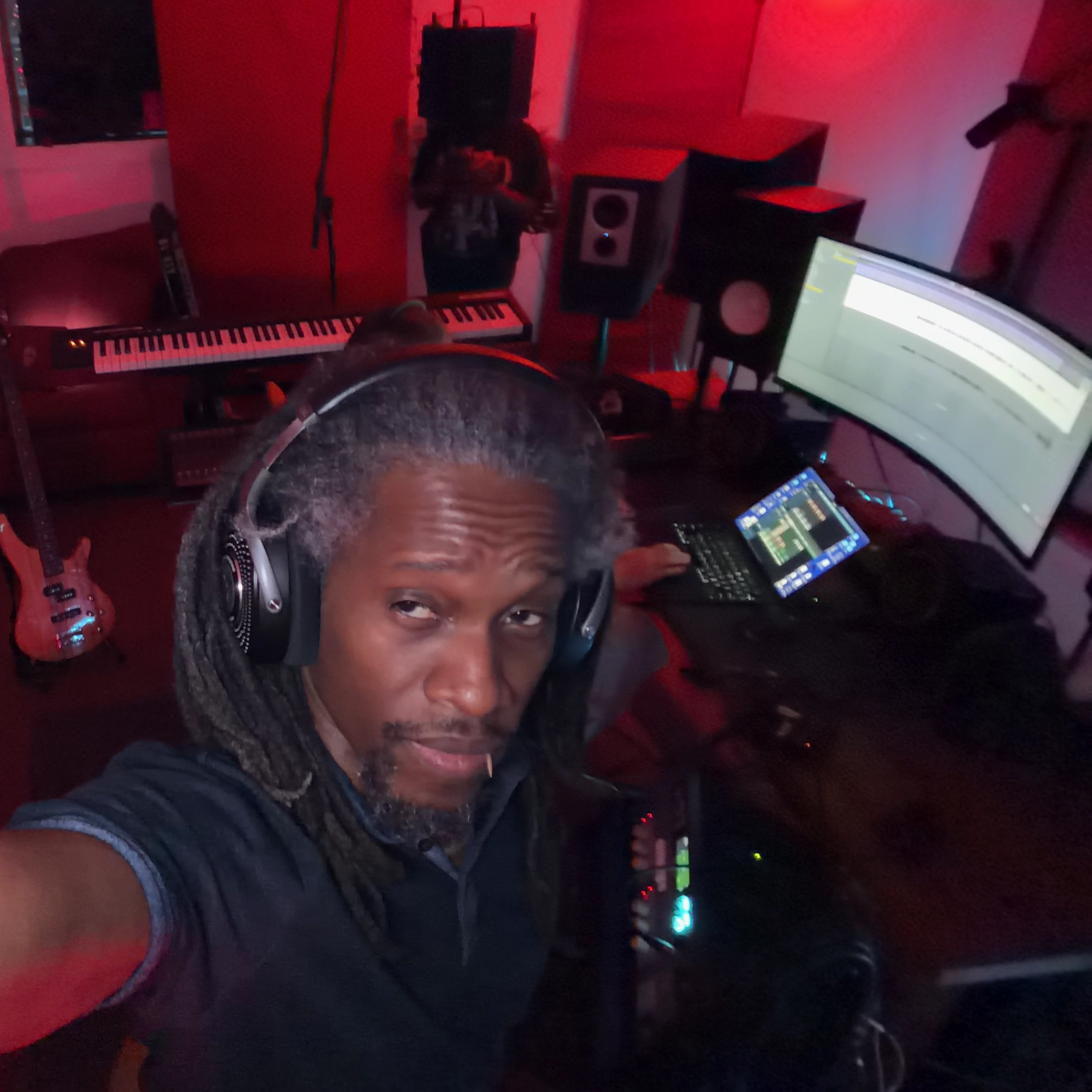 photo of Q taking a selfie with his arm extended to show an shot of the studio in the background.
